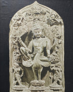 Framed stone sculpture of a deity on a textured wall