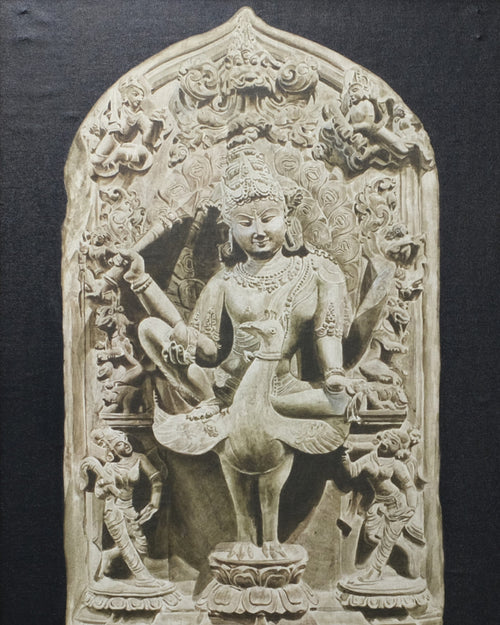 Framed stone sculpture of a deity on a textured wall