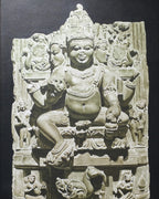 Stone sculpture of a multi-armed deity with intricate carvings on a dark background